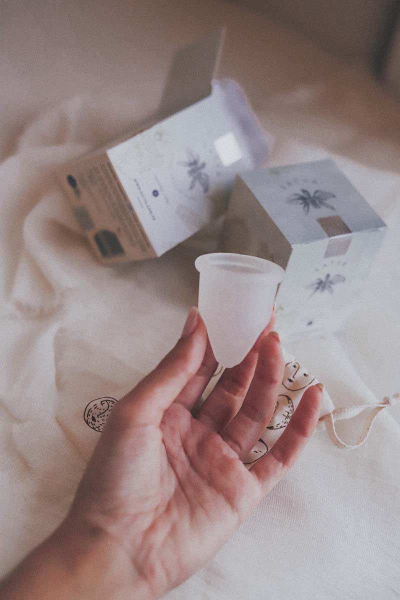 Copa menstrual Satya sostenida en mano con empaque